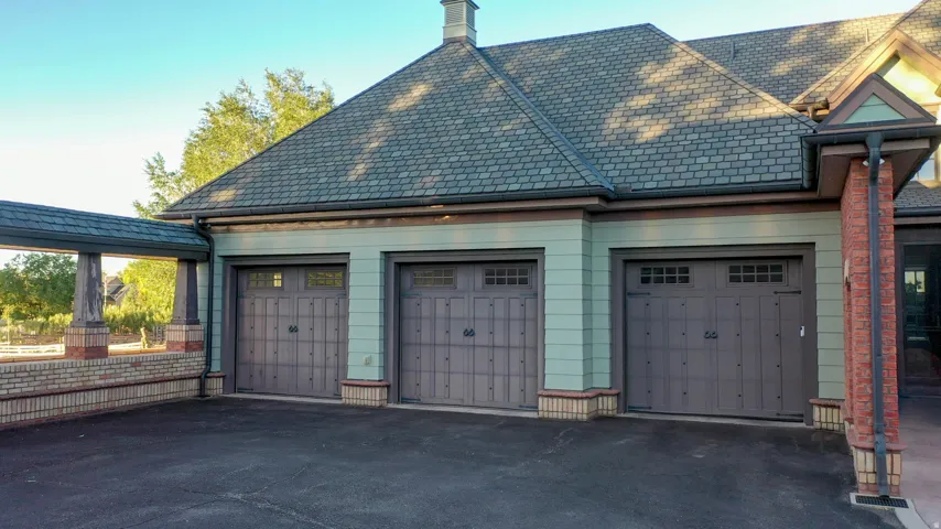 Three-car garage featuring carriage-style doors with decorative hardware and upper window panels