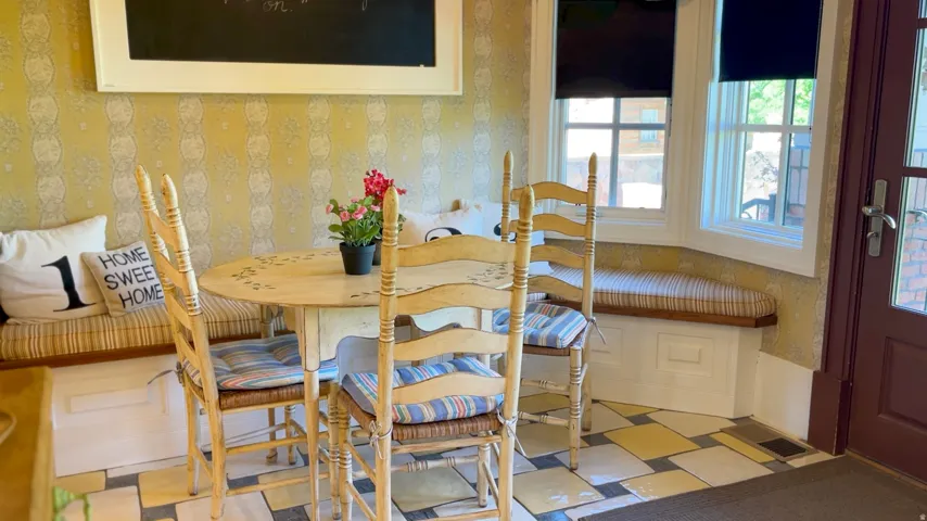 Breakfast nook featuring a built-in window seat with storage, decorative wallpaper, and a dark wood-paneled door