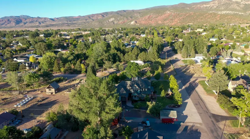 Expansive property featuring a multi-level residence with extensive landscaping, a detached outbuilding, and mature trees
