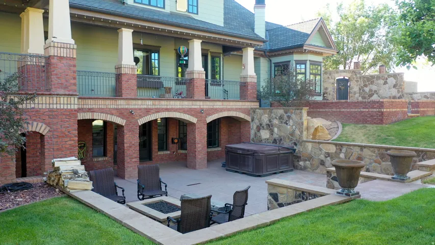 Multi-level outdoor living space featuring a covered patio with brick archways, a ground-level concrete patio, and a built-in fire pit area