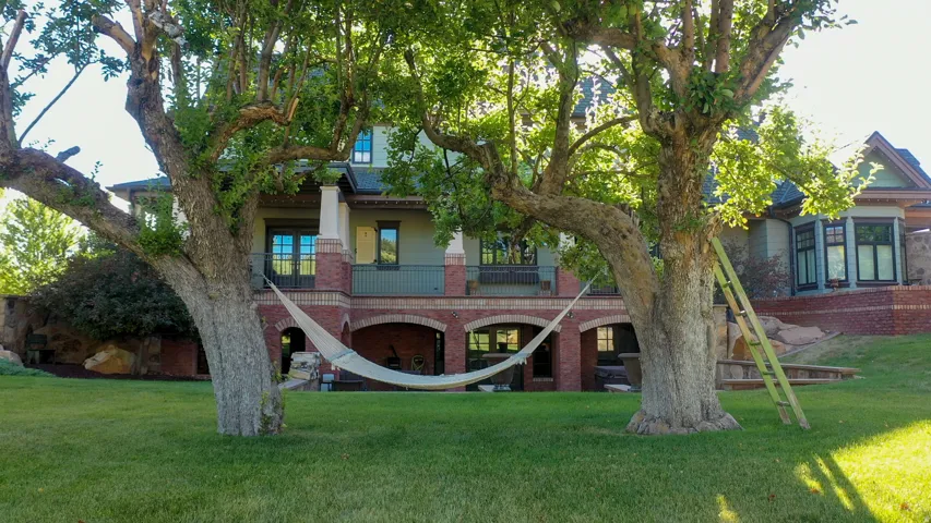 Expansive green lawn with mature trees framing a multi-story residence