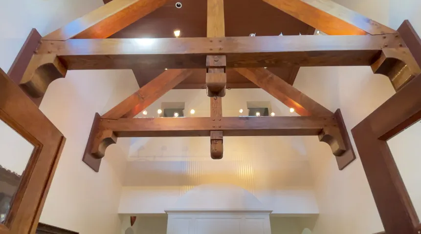Exposed wood ceiling beams with decorative corbels, recessed lighting, and a high vaulted ceiling