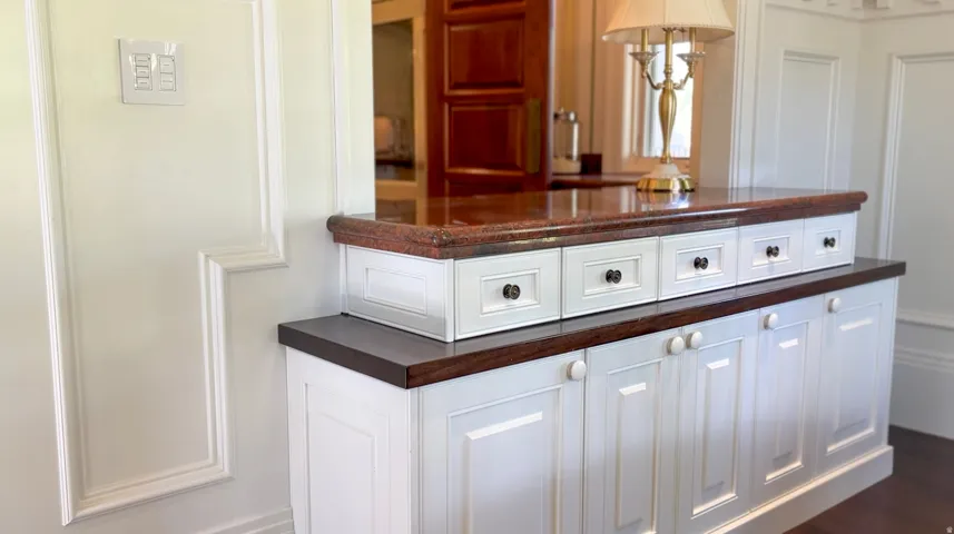 Built-in cabinetry featuring white shaker-style doors and drawers, dark wood-finish countertops, and a polished stone upper counter