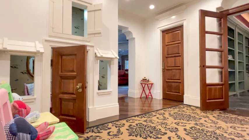 Hardwood flooring throughout the entry, featuring a decorative area rug and a solid wood paneled door