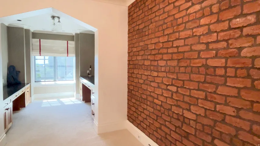 Exposed brick accent wall complementing an arched entryway leading to a separate alcove