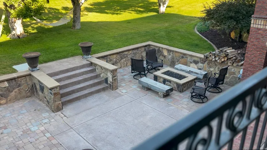 Hardscaped patio area featuring a built-in fire pit, stone accent wall, and paver stone flooring