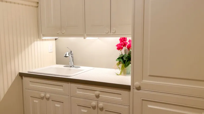 Utility sink with chrome faucet, integrated into a countertop with under-cabinet lighting