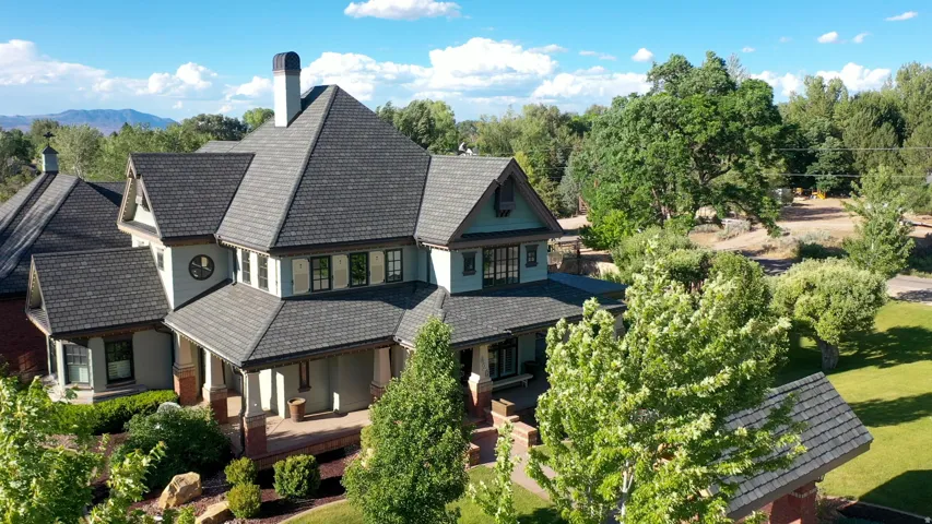 Multi-level residence featuring a prominent gabled roofline with dark shingles, light blue siding, and dark trim