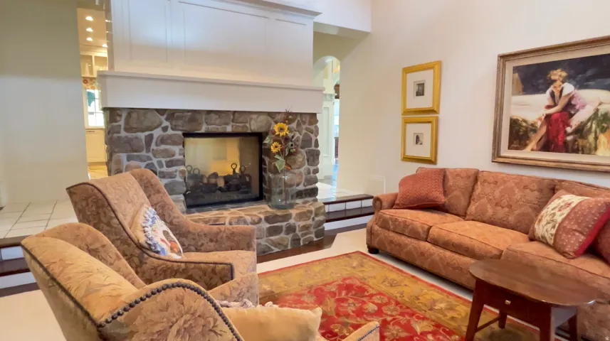 Living area featuring a floor-to-ceiling stone fireplace with a white mantel and paneling