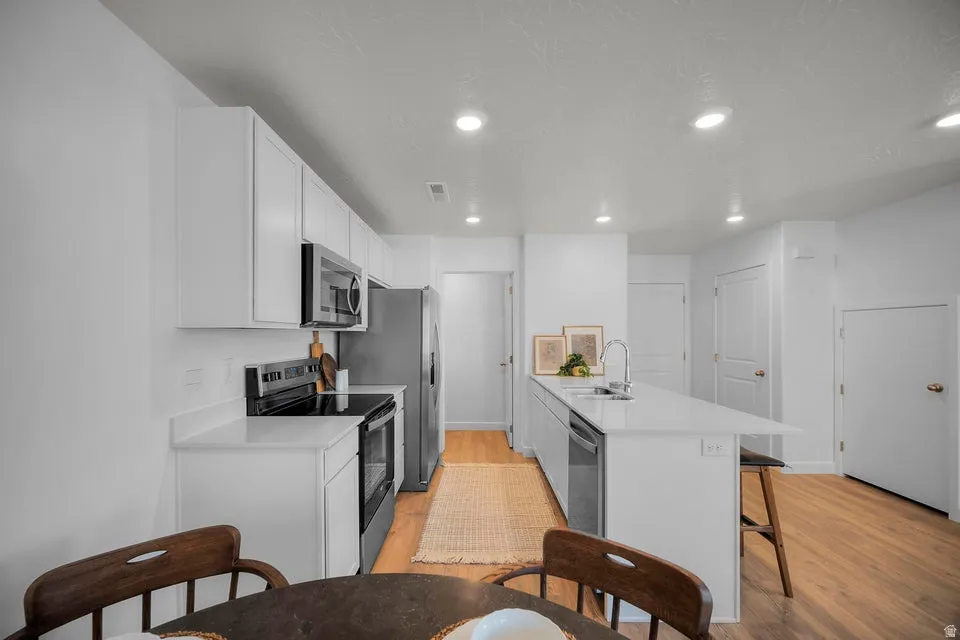 Modern kitchen featuring white cabinetry, light countertops, and wood-finish flooring