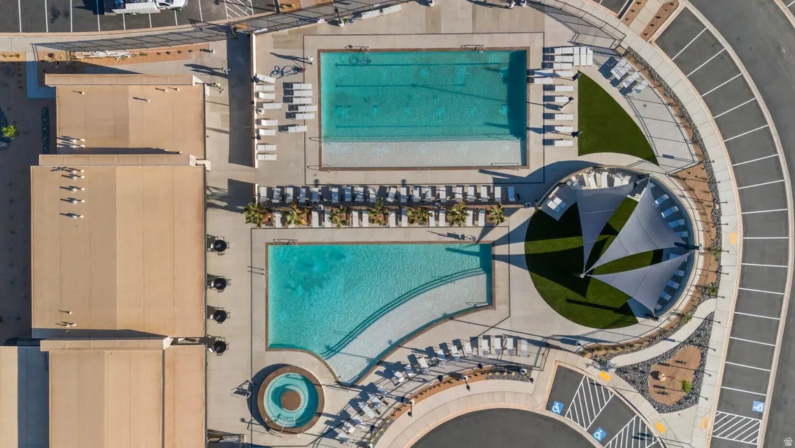Dual swimming pools with adjacent spa, expansive paved decking, and artificial turf lounge areas