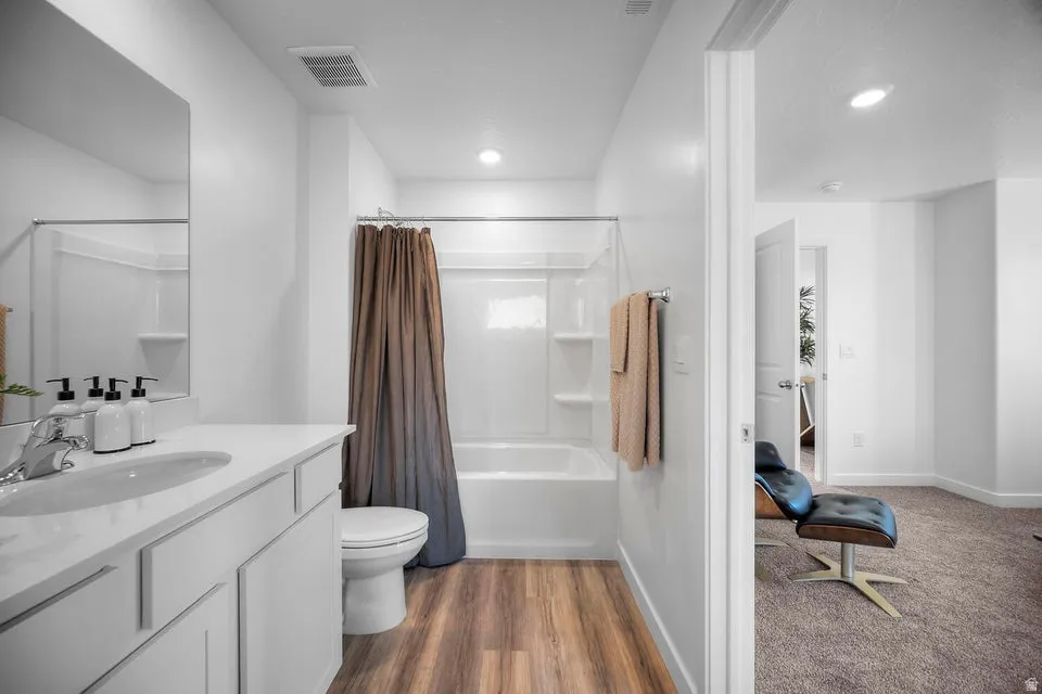 Bathroom featuring a white vanity with an integrated sink, polished chrome faucet, and wood-finish flooring