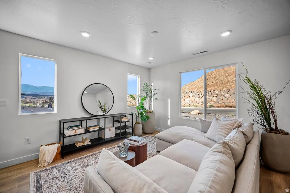 Bright living area featuring white walls, recessed lighting, and wood-finish flooring