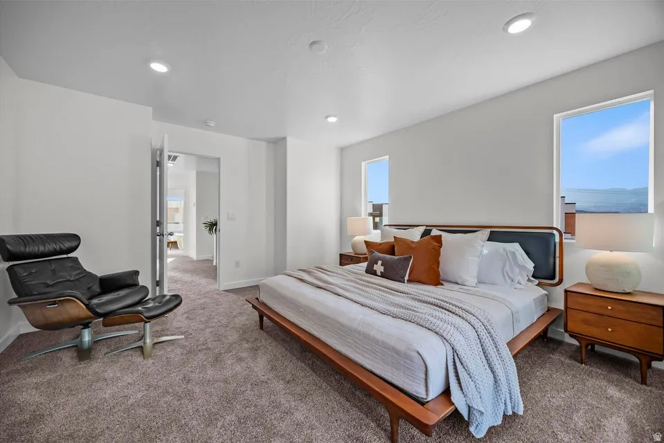 Spacious bedroom featuring neutral carpeting, recessed ceiling lighting, and multiple windows providing natural illumination