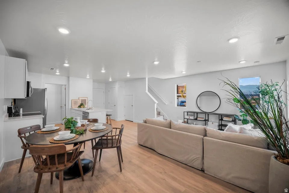 Spacious open-concept living area featuring wood-finish flooring, recessed lighting, and a kitchen island with a sink