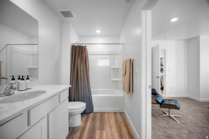 Bathroom featuring a white vanity with an integrated sink, polished chrome faucet, and wood-finish flooring