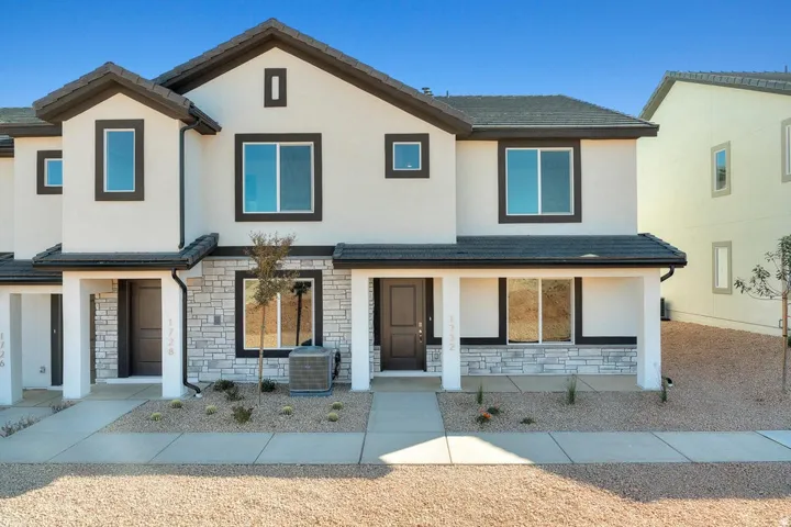 Contemporary townhome exterior featuring light stucco siding with dark trim accents