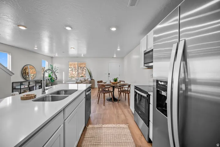 Modern kitchen featuring light-toned cabinetry, stainless steel appliances, a double basin sink, and ample countertop space