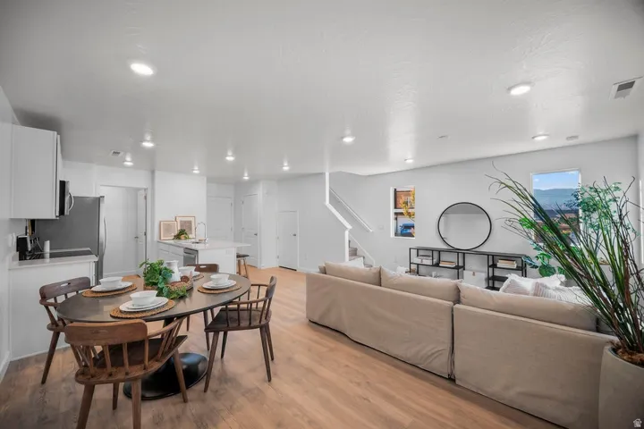Spacious open-concept living area featuring wood-finish flooring, recessed lighting, and a kitchen island with a sink