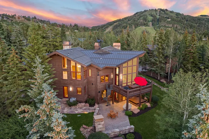 Cedar-sided mountain home featuring a metal roof, extensive decking, and a stone patio
