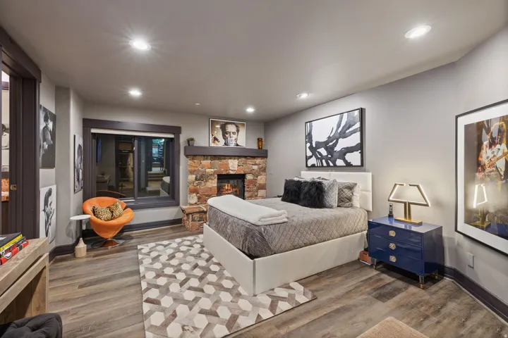 Bedroom featuring a stone fireplace with wood mantel, wood-finish flooring, recessed lighting, and a large window