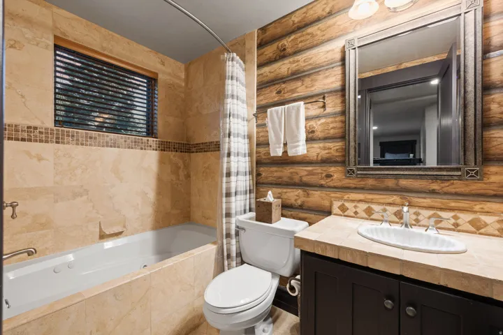 Bathroom featuring a jetted tub, a vanity with a dark wood-finish cabinet, and a tiled countertop