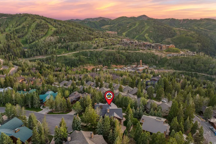 Aerial perspective showcasing a residential community nestled within a mountainous, heavily forested landscape