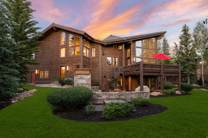 Expansive multi-level wood-clad residence featuring a spacious elevated deck with a spiral staircase