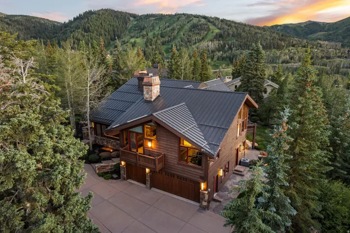 Mountain-style residence featuring a dark metal roof, wood siding, and stone accents