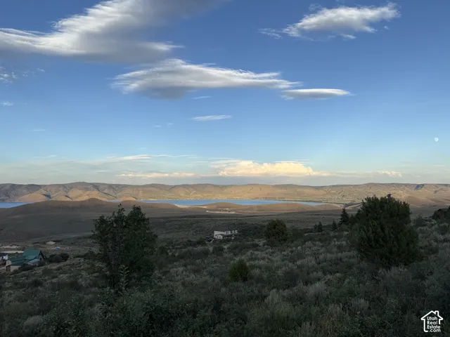 Expansive landscape featuring rolling mountain terrain, a natural reservoir, and native high-desert vegetation