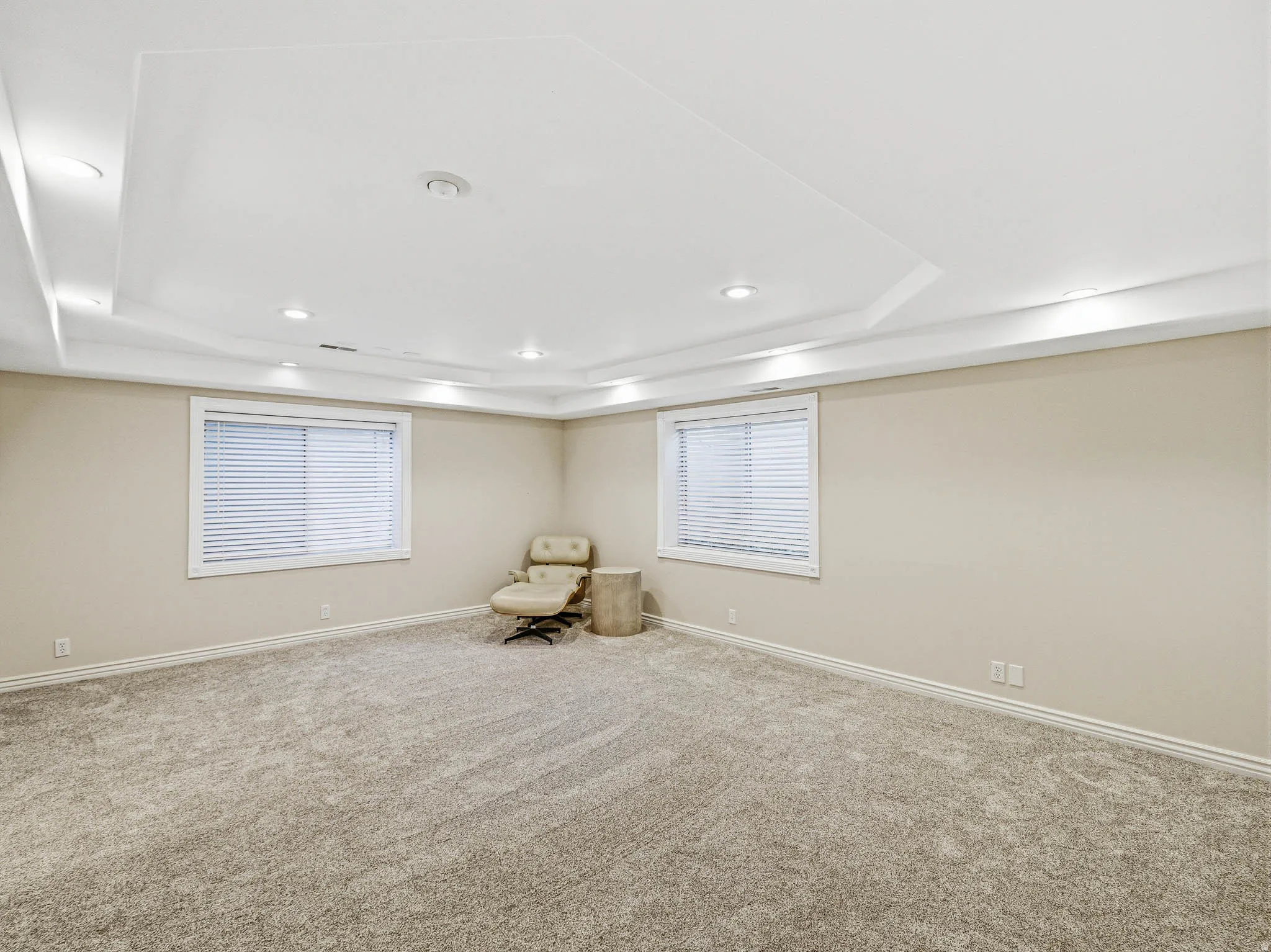 Spacious room featuring tray ceilings, recessed lighting, and wall-to-wall carpeting