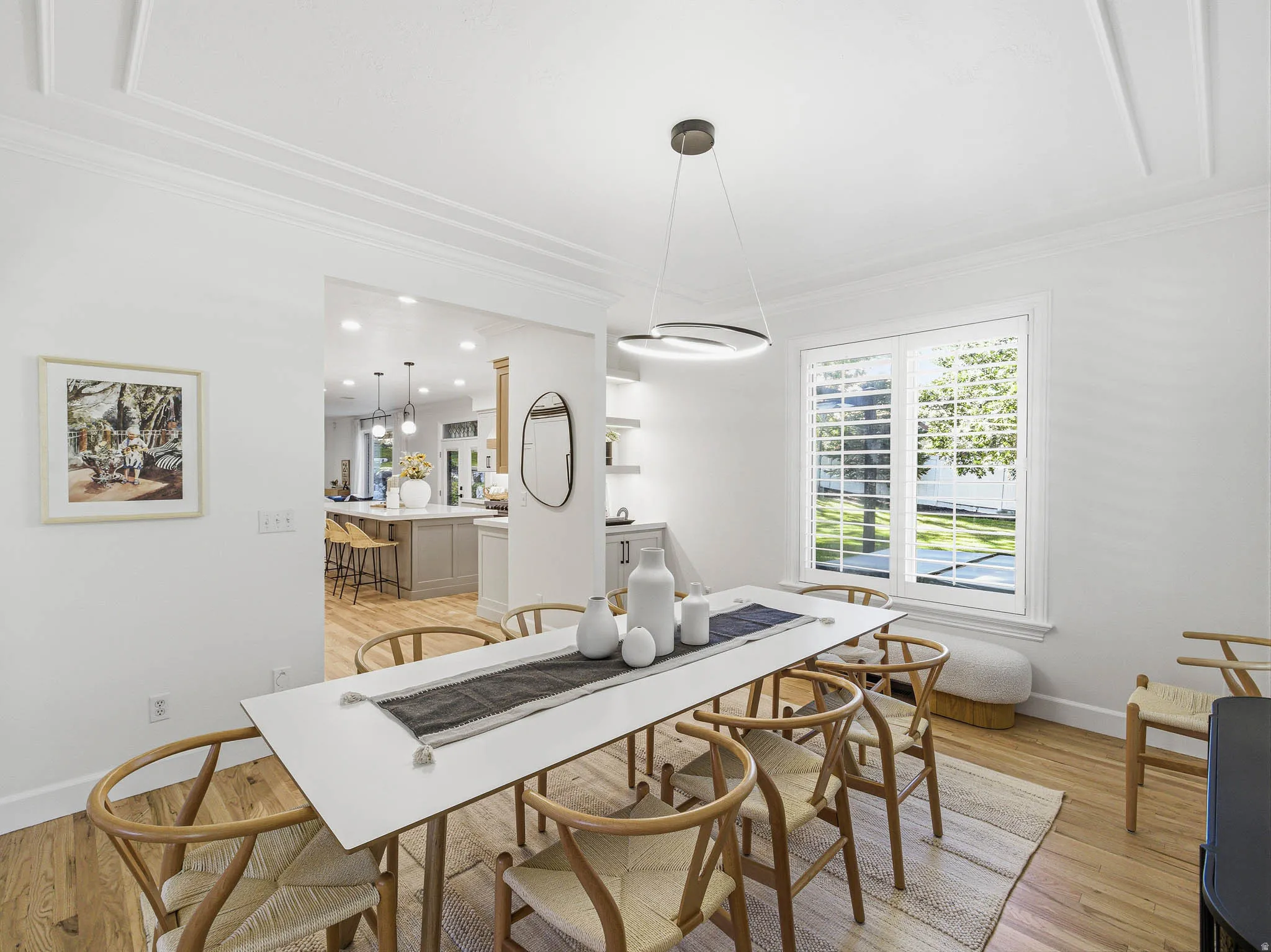 Dining area featuring wood-finish flooring, a contemporary pendant light fixture, and a large window with white plantation shutters