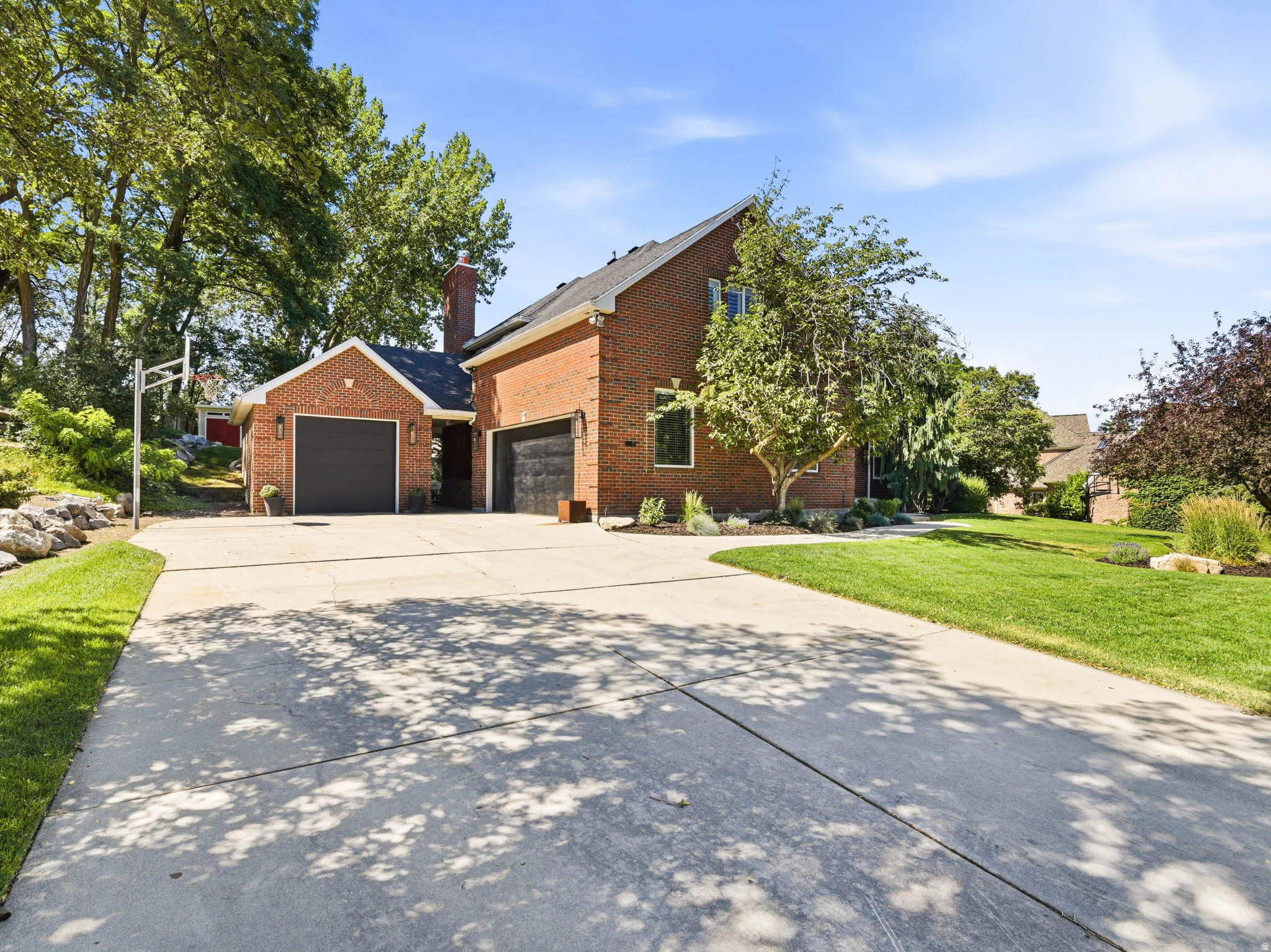Expansive concrete driveway leading to a brick residence with multiple garage bays