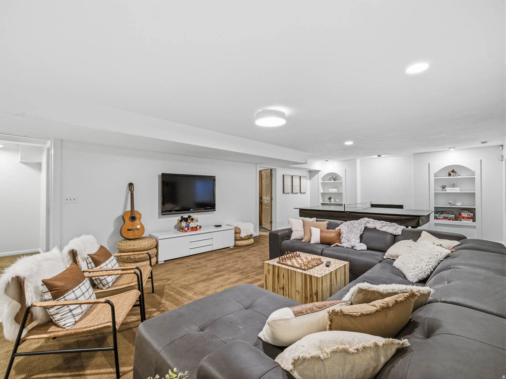 Spacious lower level featuring recessed lighting, built-in arched shelving, a media console, and durable flooring