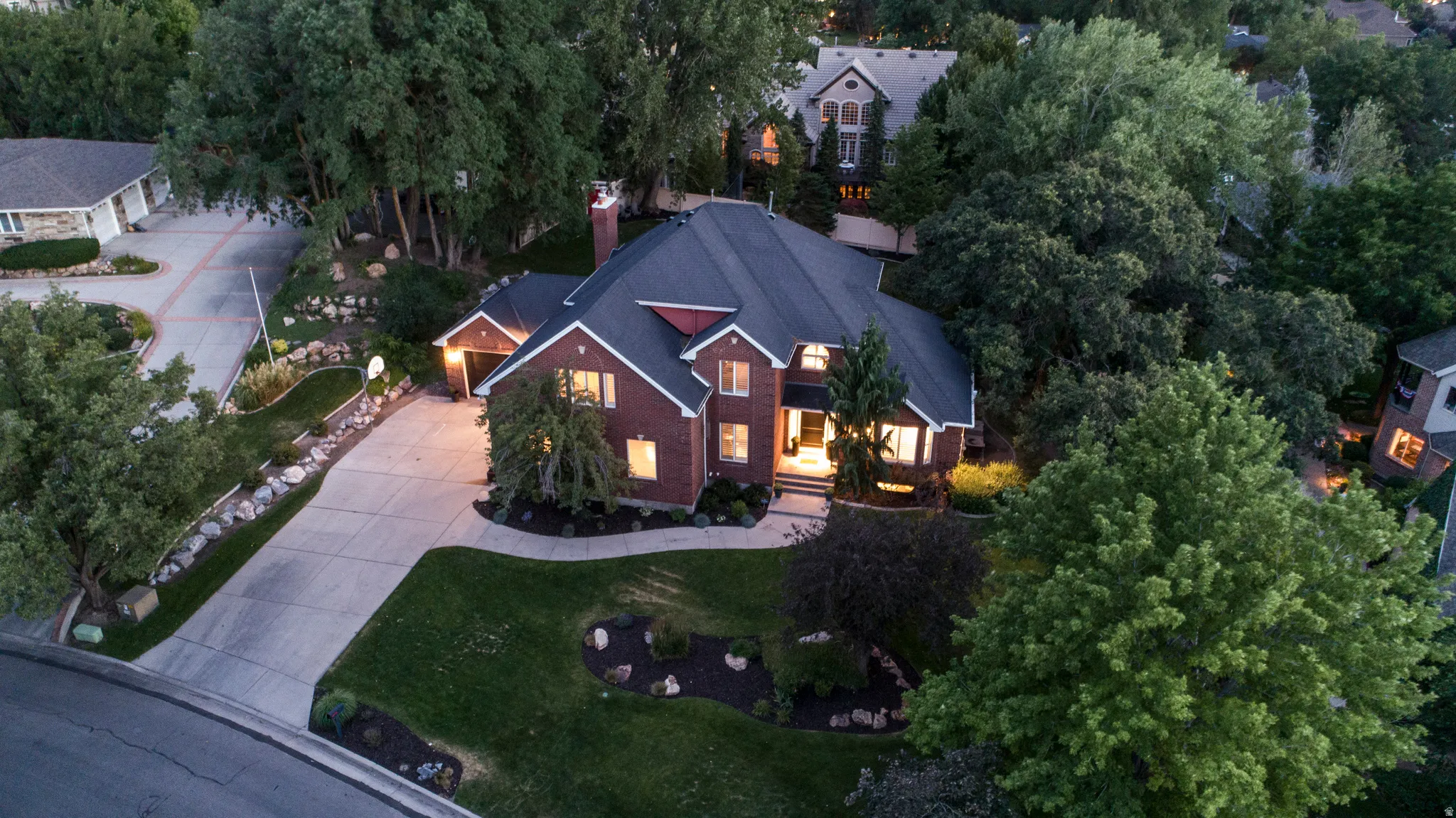 Traditional style residence featuring a dark shingle roof, brick facade, and white trim accents