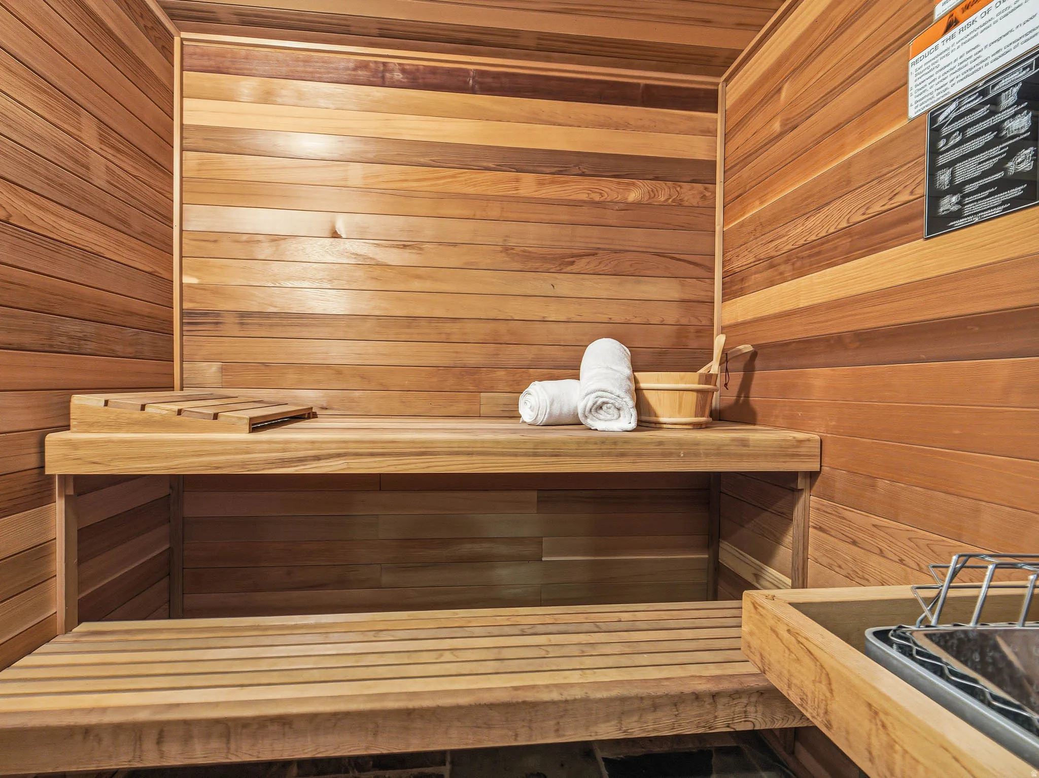 Interior sauna featuring horizontal wood paneling and multi-tiered slatted benches