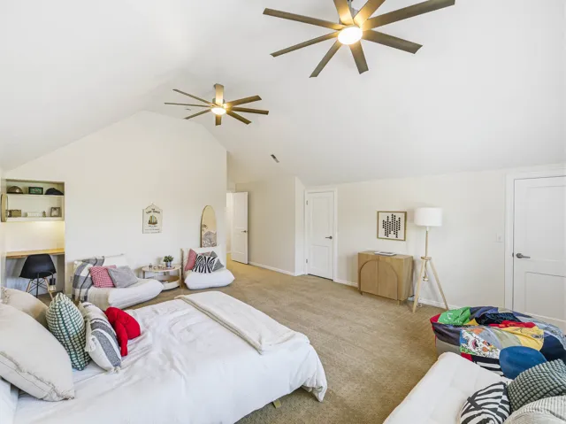 Vaulted ceiling room featuring two ceiling fans with integrated lighting