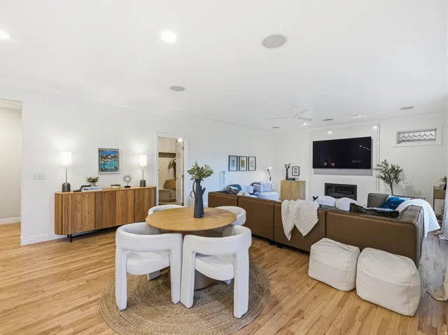 Open-concept living space featuring wood-finish flooring, recessed lighting, and a modern fireplace with a wall-mounted television above
