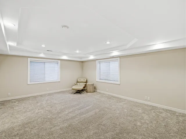 Spacious room featuring tray ceilings, recessed lighting, and wall-to-wall carpeting