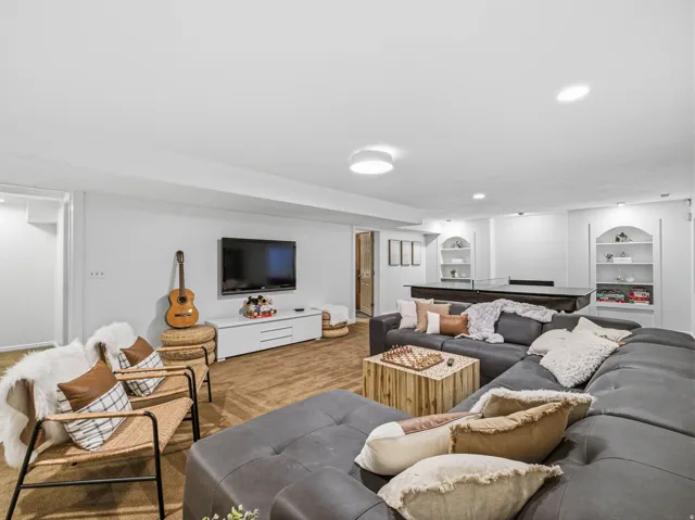 Spacious lower level featuring recessed lighting, built-in arched shelving, a media console, and durable flooring