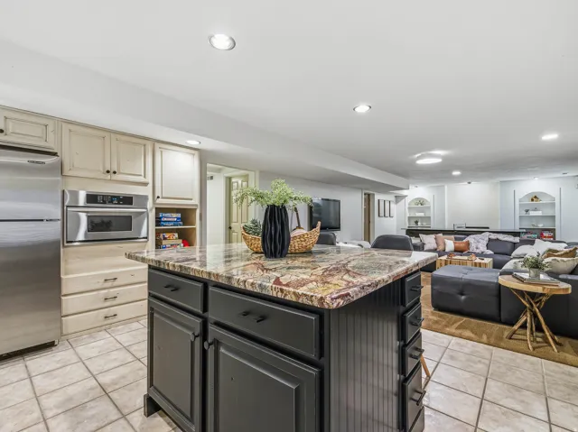 Kitchen island with a patterned countertop, beadboard paneling, and dark cabinetry