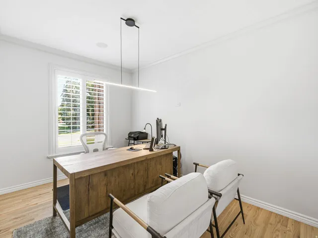 Bright interior space featuring a window with white louvered shutters, crown molding, and light wood-finish flooring