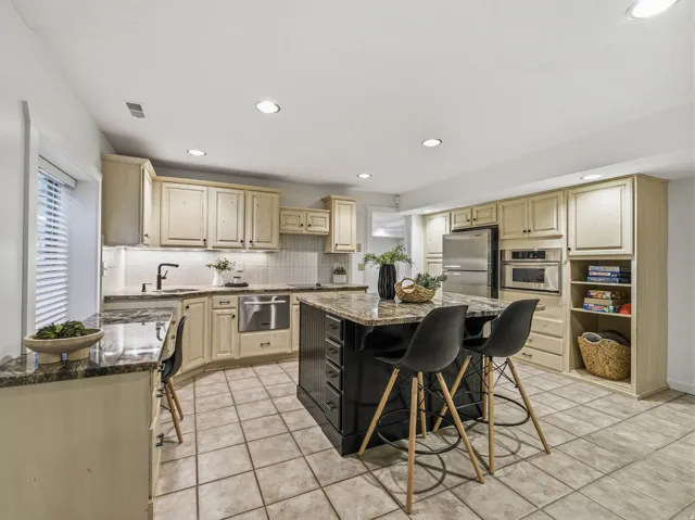 Spacious kitchen featuring an expansive center island, light-toned cabinetry, and tile flooring