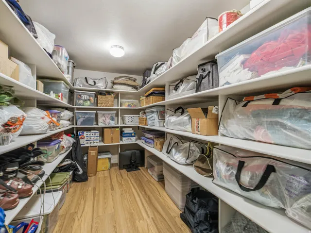 Spacious walk-in closet featuring extensive built-in shelving, wood-finish flooring, and recessed ceiling lighting