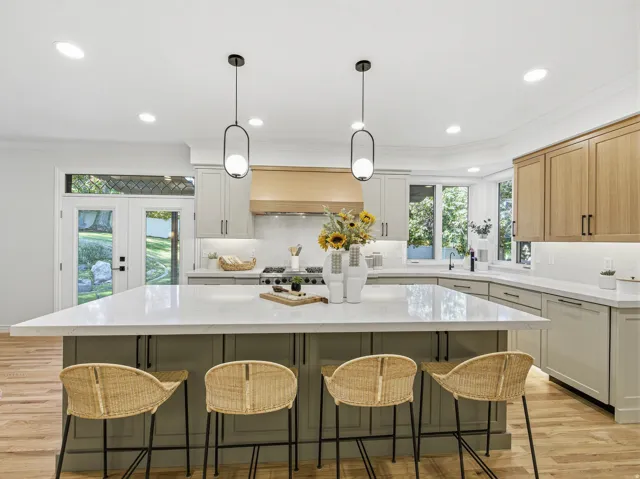 Spacious kitchen featuring a large central island with seating, light wood-finish flooring, recessed lighting, and dual pendant fixtures
