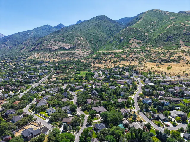 Expansive aerial showcasing a residential community nestled at the base of lush, verdant mountains