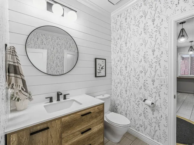 Bathroom featuring a wood-finish vanity with black hardware, white countertop, and an undermount sink