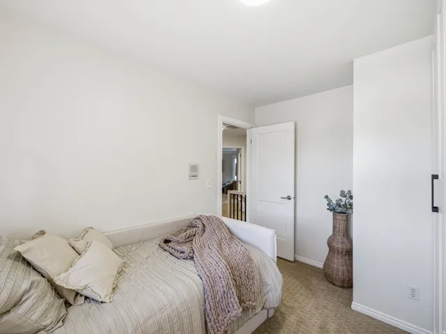Neutrally painted interior room featuring textured carpeting, white baseboards, and a contemporary flush-mount ceiling light