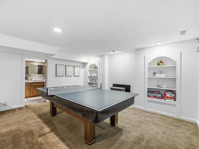 Carpeted recreational room with recessed lighting and two built-in arched bookcases