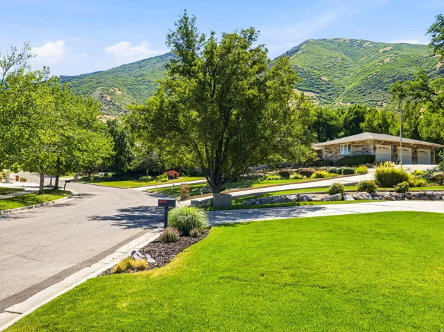 Stone-clad ranch-style residence featuring a three-car garage and manicured landscaping